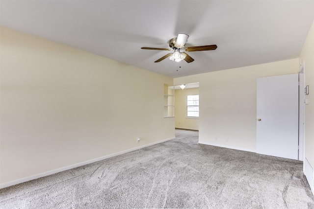 carpeted spare room featuring ceiling fan and baseboards