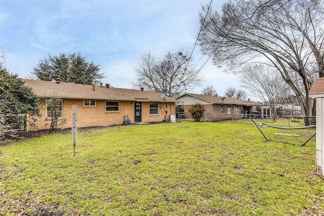 back of property with brick siding, fence, and a lawn