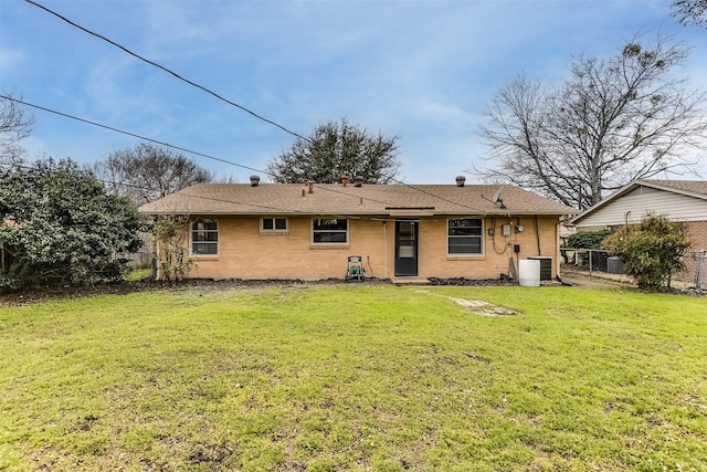 rear view of house featuring brick siding, a yard, central AC unit, and fence