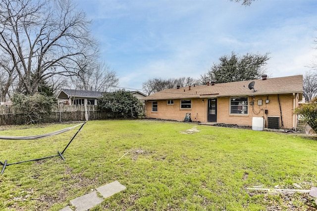 back of house with fence, a lawn, and brick siding