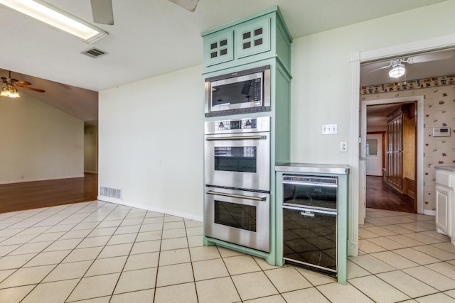 kitchen featuring stainless steel appliances, light tile patterned flooring, visible vents, and green cabinets