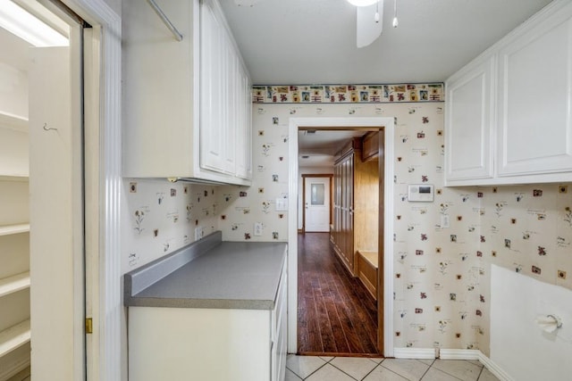 kitchen with light tile patterned floors, white cabinets, and wallpapered walls