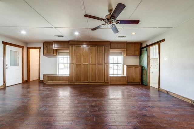 unfurnished living room featuring dark wood-type flooring, plenty of natural light, and visible vents