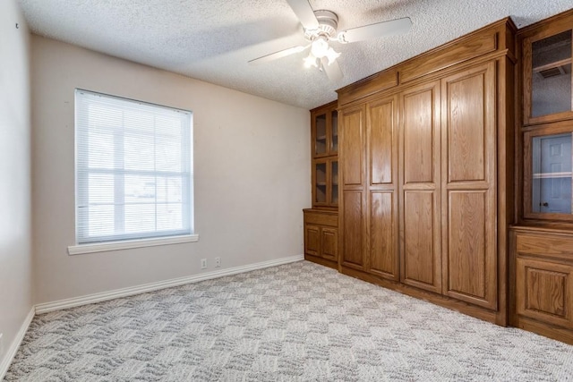 unfurnished bedroom featuring a textured ceiling, ceiling fan, carpet, and baseboards