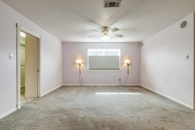 spare room with carpet floors, baseboards, visible vents, and a ceiling fan