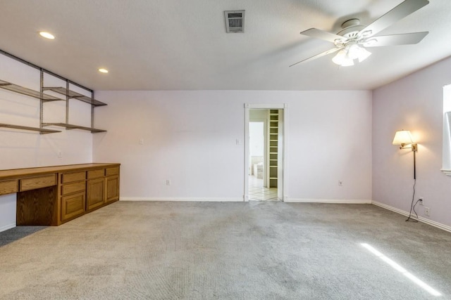 interior space featuring visible vents, baseboards, light colored carpet, built in study area, and ceiling fan