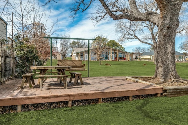 view of property's community with fence, a deck, and a lawn