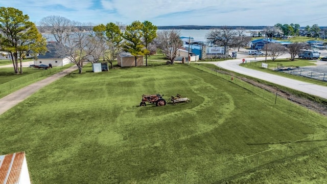 view of community featuring a water view, a yard, a shed, and an outbuilding