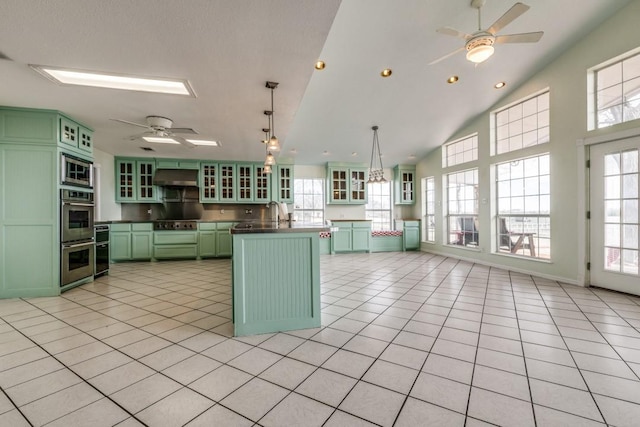 kitchen with light tile patterned floors, ceiling fan, under cabinet range hood, stainless steel appliances, and green cabinetry