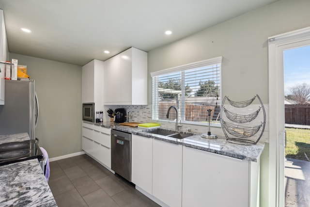 kitchen with appliances with stainless steel finishes, a sink, white cabinetry, and a healthy amount of sunlight