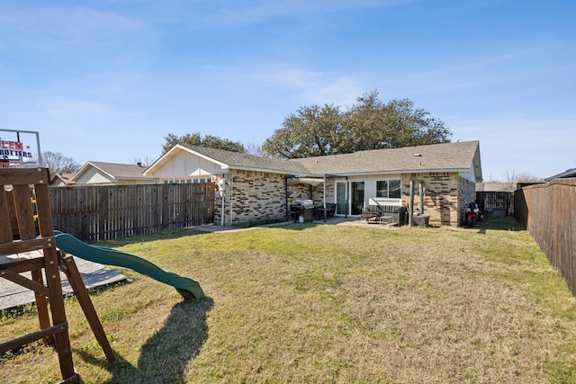 back of property with a playground, a fenced backyard, brick siding, a lawn, and a patio area