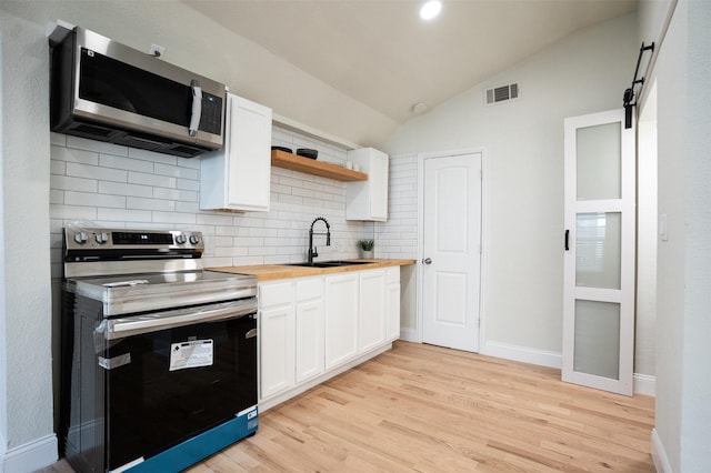 kitchen with a barn door, visible vents, appliances with stainless steel finishes, wooden counters, and a sink