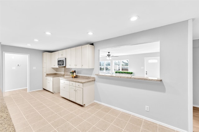 kitchen featuring baseboards, ceiling fan, stainless steel microwave, light countertops, and recessed lighting