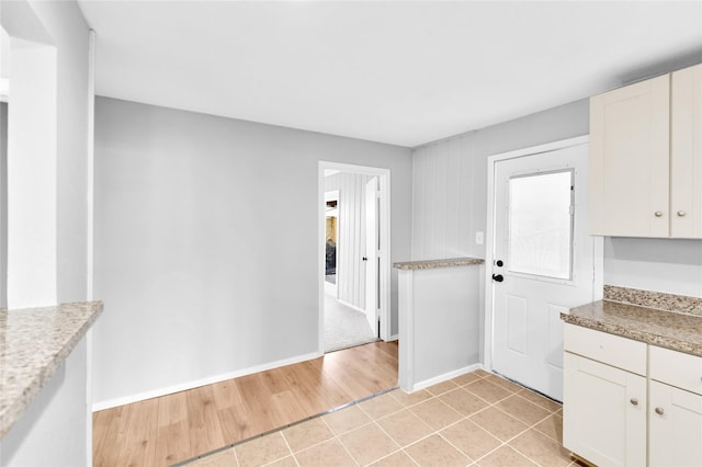 kitchen featuring light countertops, light tile patterned flooring, white cabinetry, and baseboards