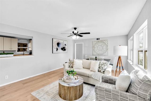 living room with baseboards, ceiling fan, visible vents, and light wood-style floors