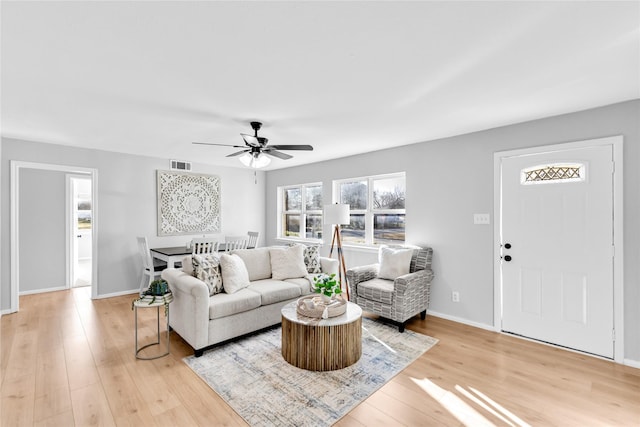 living area with light wood-style floors, baseboards, visible vents, and ceiling fan