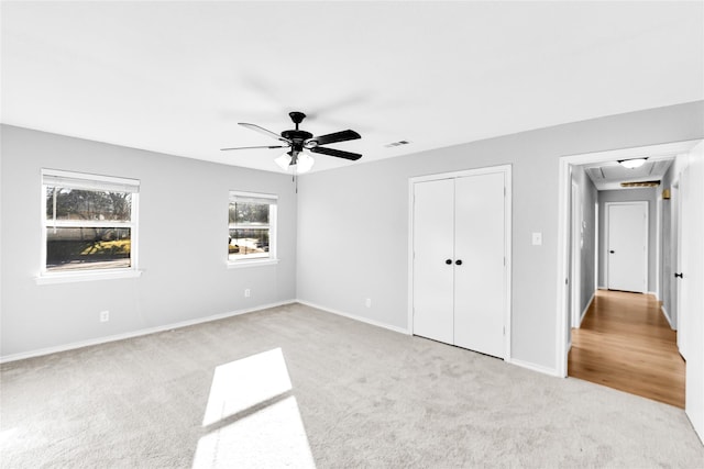 unfurnished bedroom featuring a closet, visible vents, a ceiling fan, light carpet, and baseboards