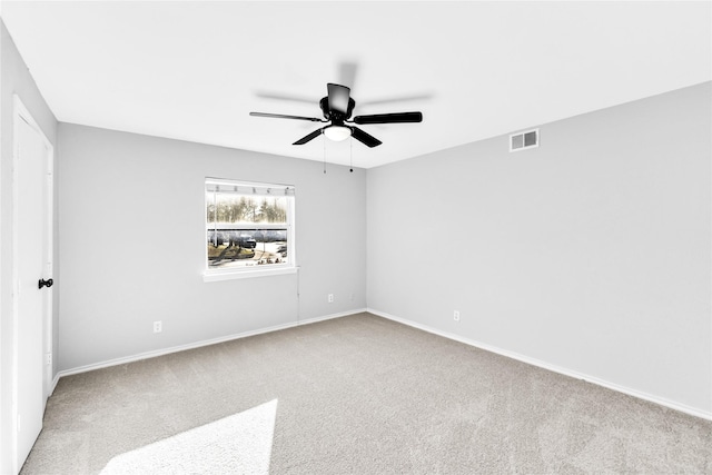 spare room featuring carpet floors, visible vents, ceiling fan, and baseboards