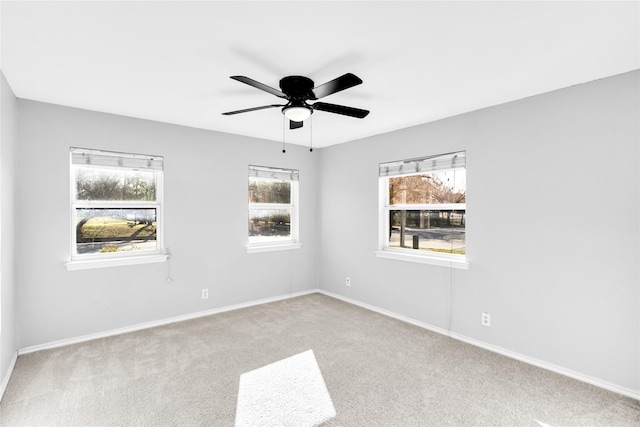 spare room with carpet, a ceiling fan, and baseboards