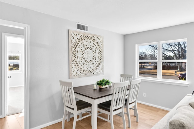 dining area featuring baseboards, light wood-style flooring, visible vents, and a wealth of natural light