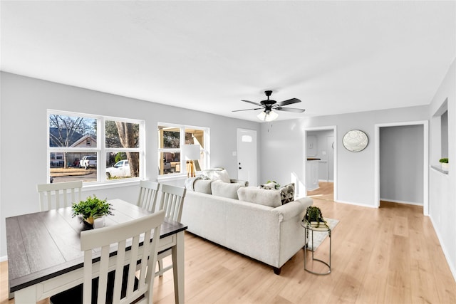 living area with a ceiling fan, light wood-type flooring, and baseboards