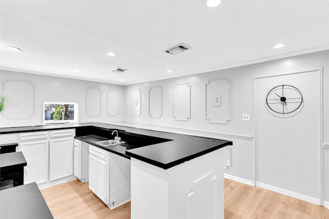 kitchen with light wood-style flooring, dark countertops, a sink, and visible vents