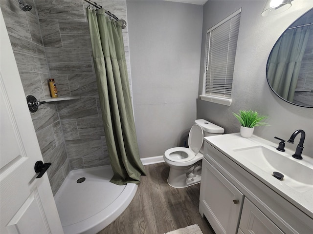 full bath with toilet, wood finished floors, vanity, baseboards, and a shower stall