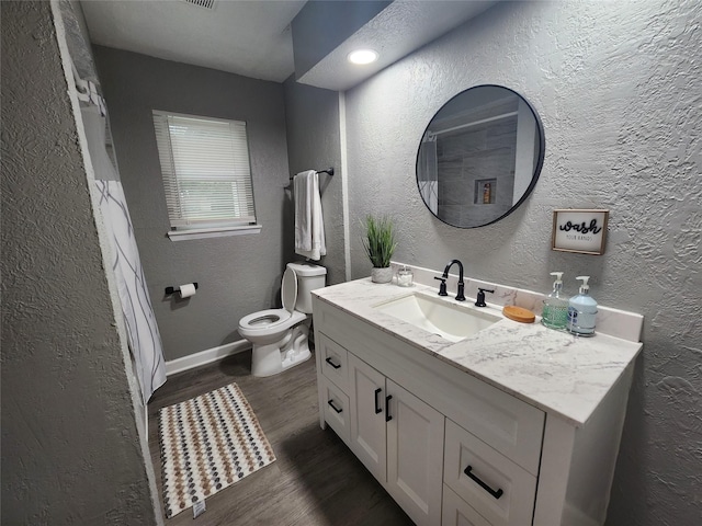 bathroom with a textured wall, wood finished floors, and toilet