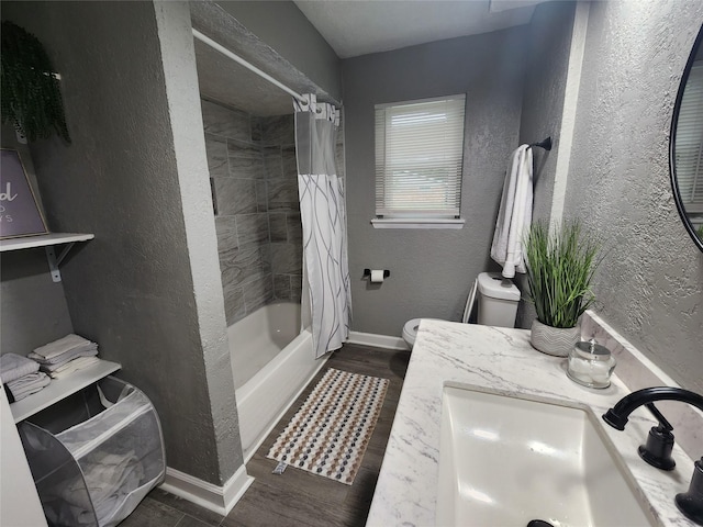 bathroom with toilet, baseboards, a sink, and a textured wall