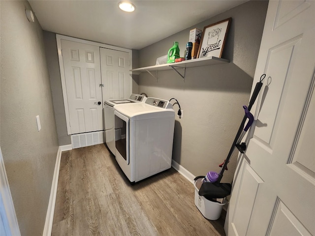 laundry area with light wood-type flooring, laundry area, baseboards, and separate washer and dryer