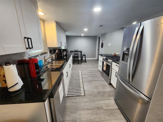 kitchen featuring appliances with stainless steel finishes, light wood-type flooring, a sink, and white cabinetry