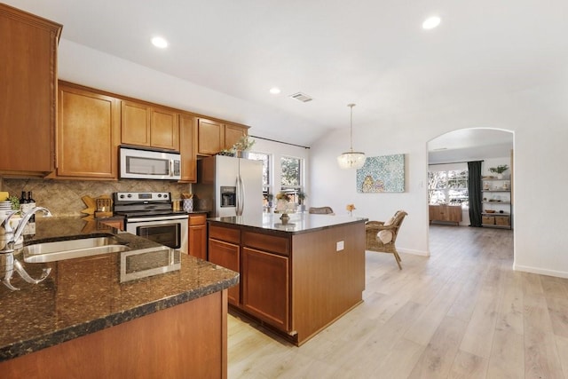 kitchen featuring arched walkways, visible vents, a sink, stainless steel appliances, and backsplash