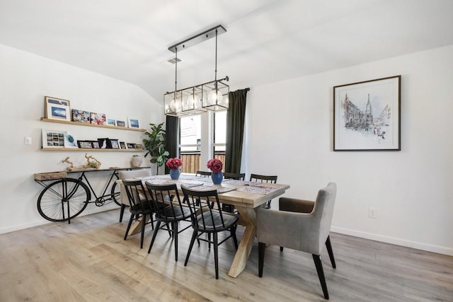 dining space with visible vents, baseboards, vaulted ceiling, and wood finished floors