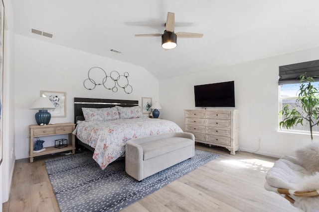 bedroom with a ceiling fan, visible vents, vaulted ceiling, and wood finished floors