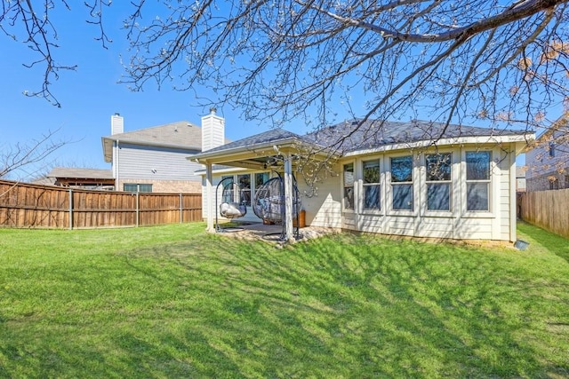 back of property with a fenced backyard and a lawn