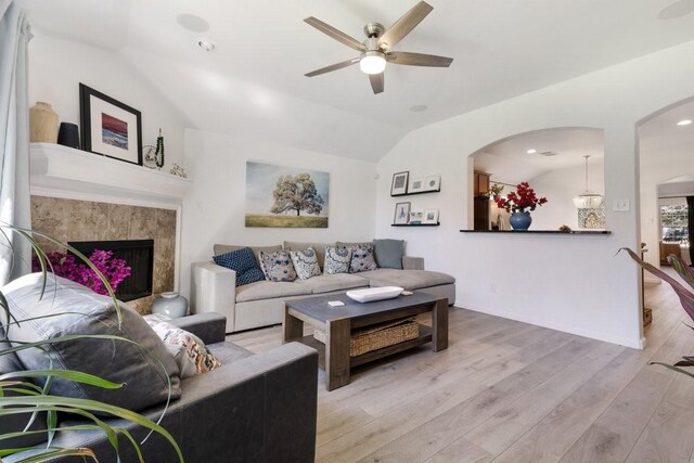 living room with a fireplace, ceiling fan, vaulted ceiling, wood finished floors, and baseboards