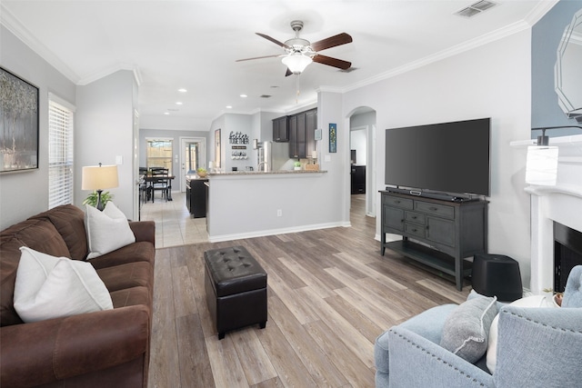 living area with arched walkways, crown molding, recessed lighting, visible vents, and light wood-type flooring