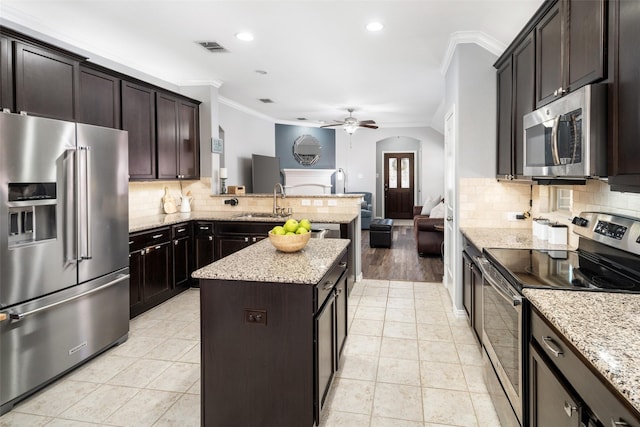 kitchen with light tile patterned flooring, stainless steel appliances, a peninsula, visible vents, and crown molding