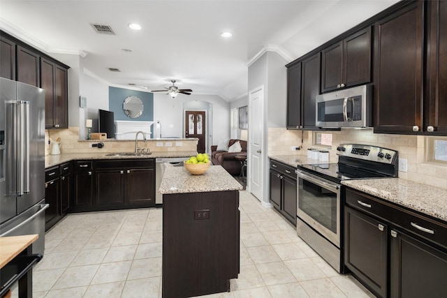 kitchen featuring a center island, crown molding, stainless steel appliances, visible vents, and a sink