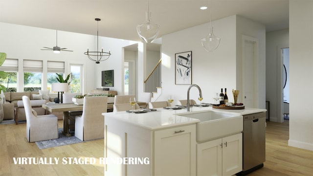 kitchen featuring hanging light fixtures, stainless steel dishwasher, open floor plan, a sink, and light wood-type flooring