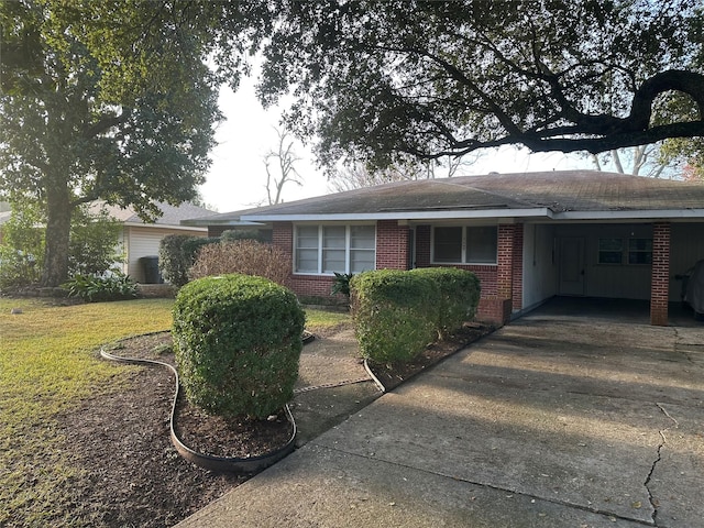 single story home with an attached carport, concrete driveway, brick siding, and a front lawn