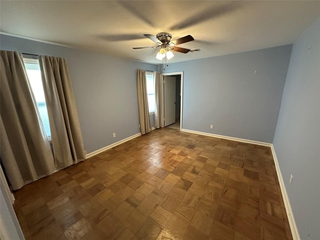 unfurnished room featuring a ceiling fan and baseboards