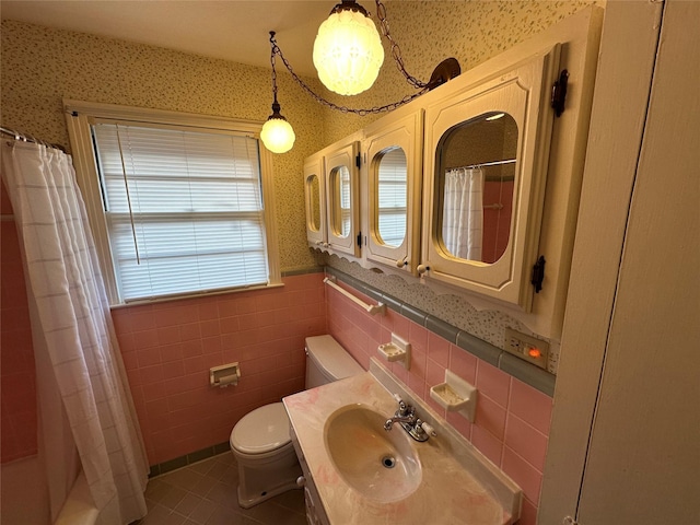 full bathroom featuring a wainscoted wall, toilet, and wallpapered walls