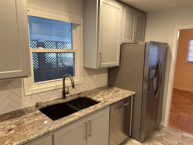 kitchen with light stone countertops, tasteful backsplash, appliances with stainless steel finishes, and a sink