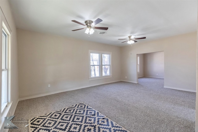 carpeted empty room with baseboards, visible vents, and ceiling fan