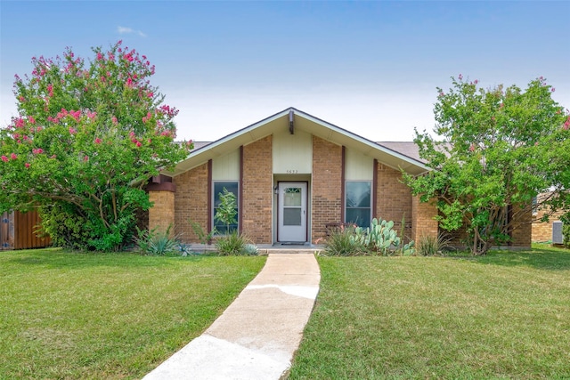 mid-century inspired home with a front yard and brick siding