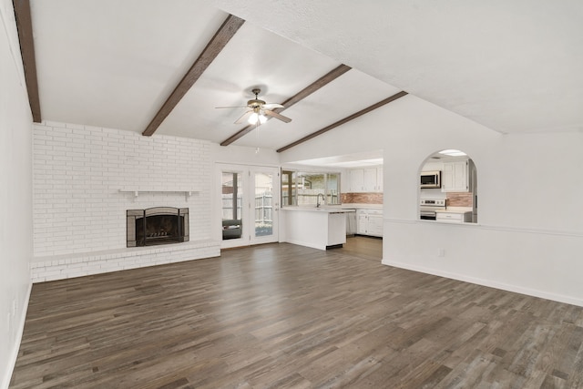 unfurnished living room featuring a fireplace, dark wood finished floors, lofted ceiling with beams, and ceiling fan