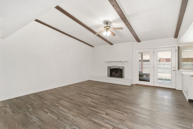 unfurnished living room with lofted ceiling with beams, wood finished floors, a ceiling fan, baseboards, and a brick fireplace