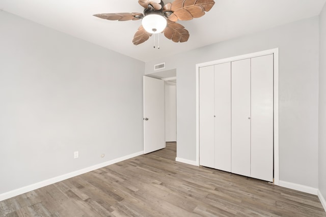 unfurnished bedroom featuring baseboards, a closet, visible vents, and wood finished floors