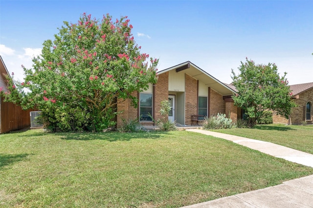 view of front facade with a front yard, fence, and brick siding